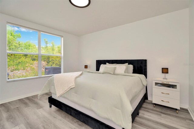 bedroom featuring baseboards, light wood-style flooring, and multiple windows