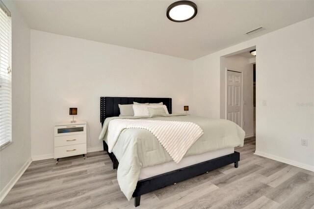 bedroom with light wood finished floors, baseboards, and multiple windows
