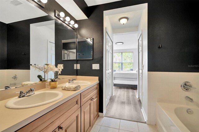 ensuite bathroom featuring tile patterned flooring, a bath, and double vanity