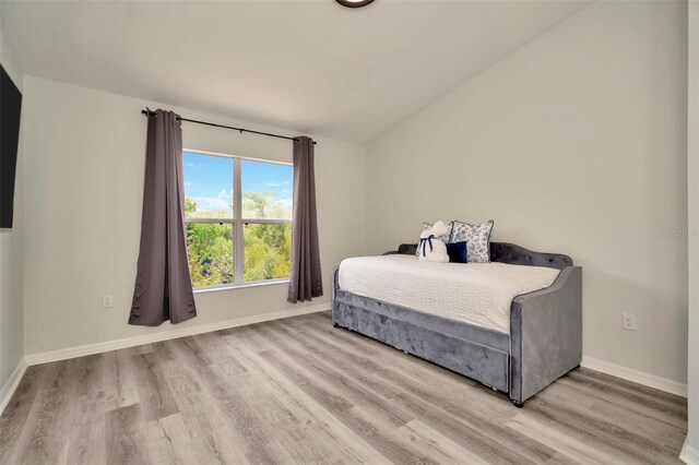 bedroom featuring vaulted ceiling, wood finished floors, and baseboards