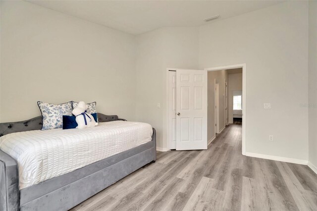 bedroom featuring wood finished floors, baseboards, and vaulted ceiling