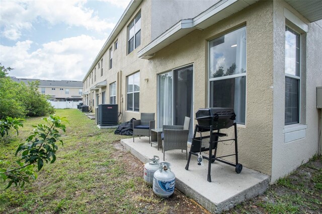 view of green lawn with central AC unit and a patio area