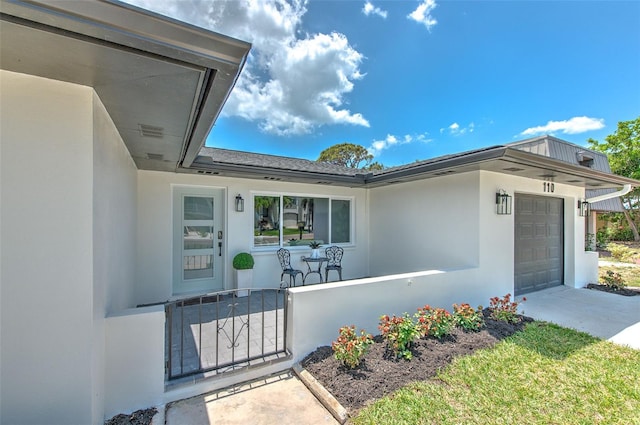 property entrance featuring stucco siding, a garage, fence, and concrete driveway