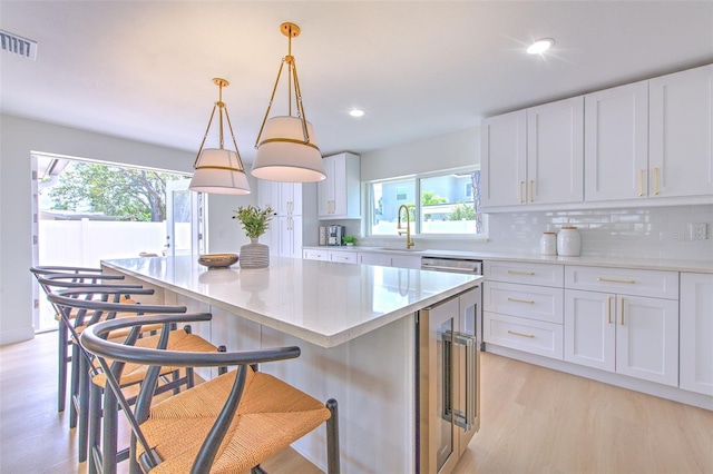 kitchen featuring visible vents, a sink, a healthy amount of sunlight, and light wood-type flooring