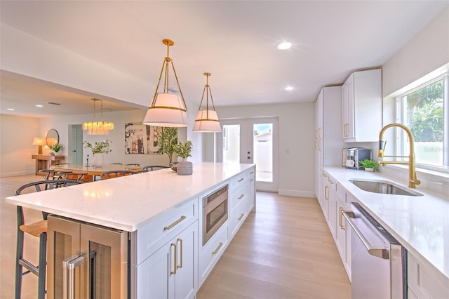 kitchen with light stone countertops, a sink, a breakfast bar, stainless steel appliances, and white cabinetry