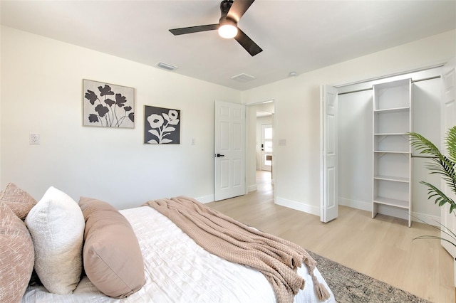 bedroom featuring ceiling fan, light wood-style floors, baseboards, visible vents, and a closet