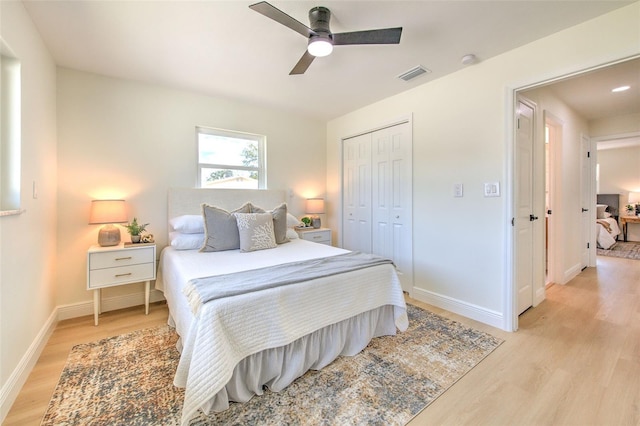 bedroom with light wood finished floors, a ceiling fan, baseboards, visible vents, and a closet