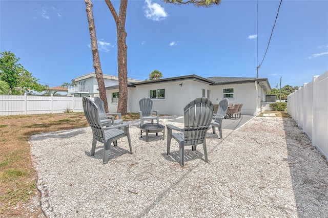 rear view of house featuring a fenced backyard, a patio, stucco siding, and an outdoor fire pit