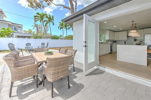 view of patio with fence, a sink, outdoor dining area, and area for grilling