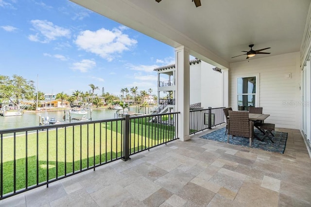 balcony with outdoor dining space, a patio area, a water view, and a ceiling fan