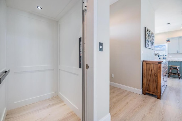 hallway with baseboards, elevator, light wood finished floors, and recessed lighting