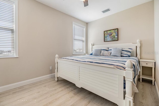 bedroom with ceiling fan, light wood-style flooring, baseboards, and visible vents