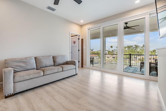 living area featuring light wood-style floors, visible vents, and a ceiling fan