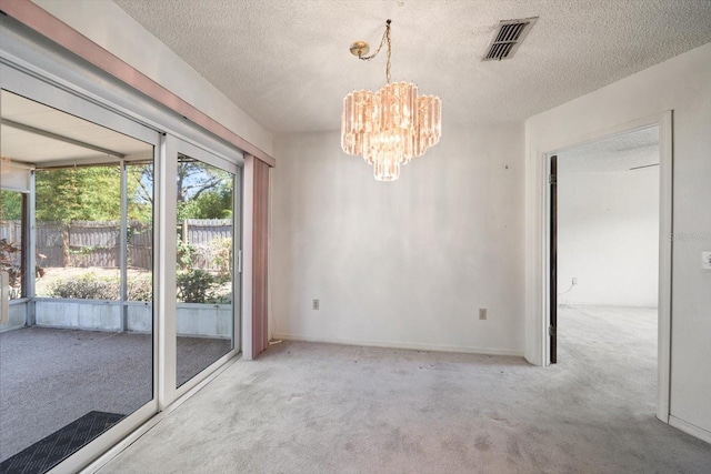 unfurnished dining area featuring a textured ceiling, a notable chandelier, visible vents, and carpet floors
