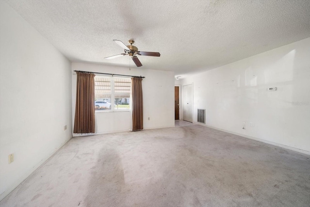 carpeted empty room featuring a textured ceiling, visible vents, and a ceiling fan