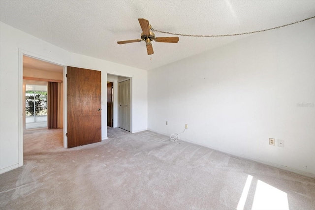 unfurnished bedroom featuring light carpet, a textured ceiling, and a ceiling fan
