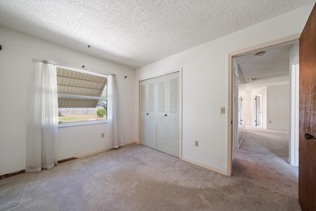 unfurnished bedroom with baseboards, carpet flooring, a closet, and a textured ceiling