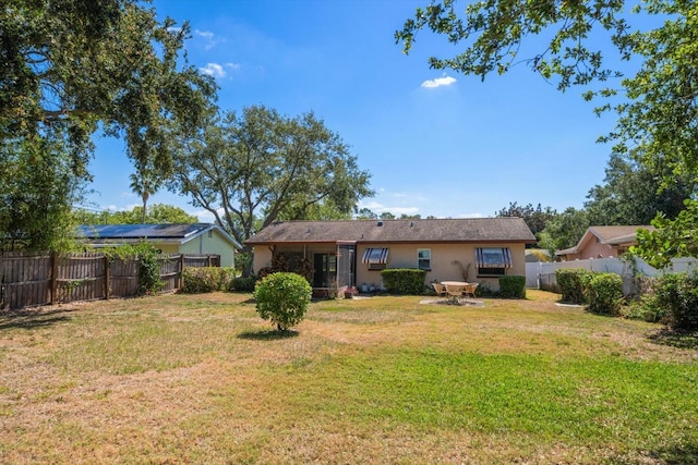 rear view of house with a yard, a fenced backyard, and stucco siding