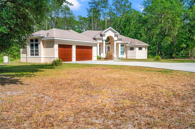 7340 W Dr, Wesley Chapel, FL 33544 - view of front facade with concrete driveway, a garage, stucco siding, and a front lawn