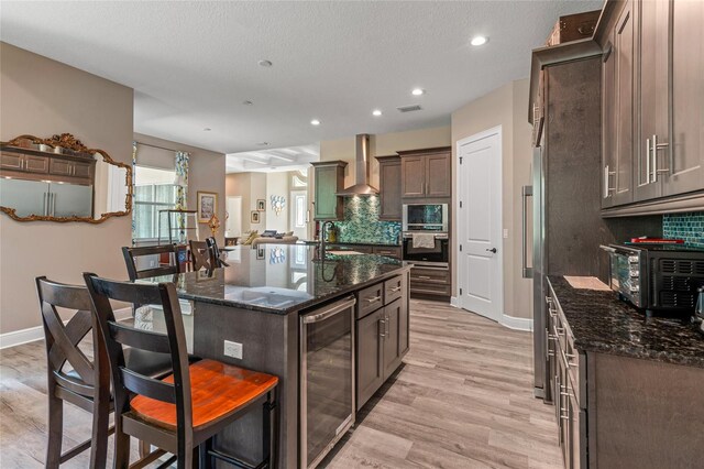 7340 W Dr, Wesley Chapel, FL 33544 - kitchen featuring wall chimney range hood, decorative backsplash, a breakfast bar area, and beverage cooler