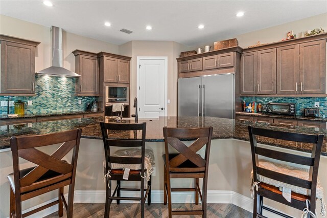 7340 W Dr, Wesley Chapel, FL 33544 - kitchen with built in appliances, tasteful backsplash, visible vents, wall chimney exhaust hood, and dark brown cabinetry