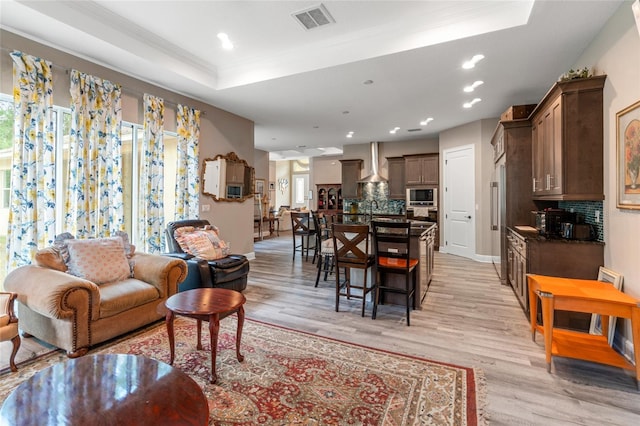 7340 W Dr, Wesley Chapel, FL 33544 - living room with visible vents, light wood-style flooring, a raised ceiling, and ornamental molding