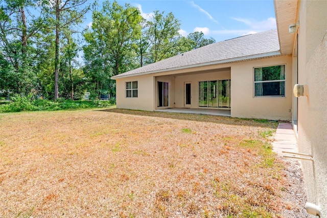 7340 W Dr, Wesley Chapel, FL 33544 - back of house with a yard, a patio area, stucco siding, and roof with shingles