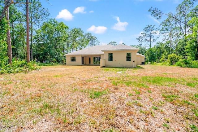 7340 W Dr, Wesley Chapel, FL 33544 - rear view of property with stucco siding and a lawn