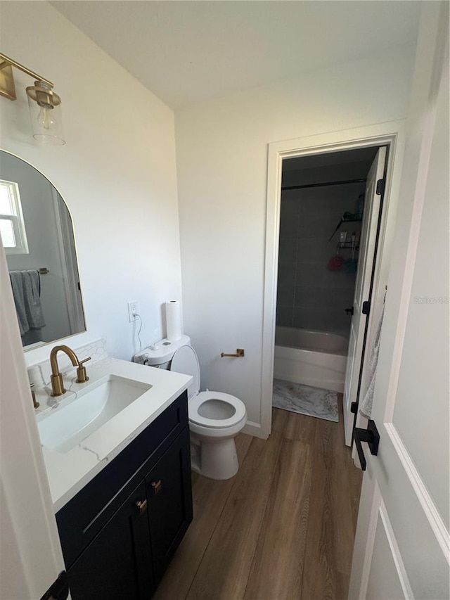 bathroom featuring vanity, wood finished floors, toilet, walk in shower, and a tub
