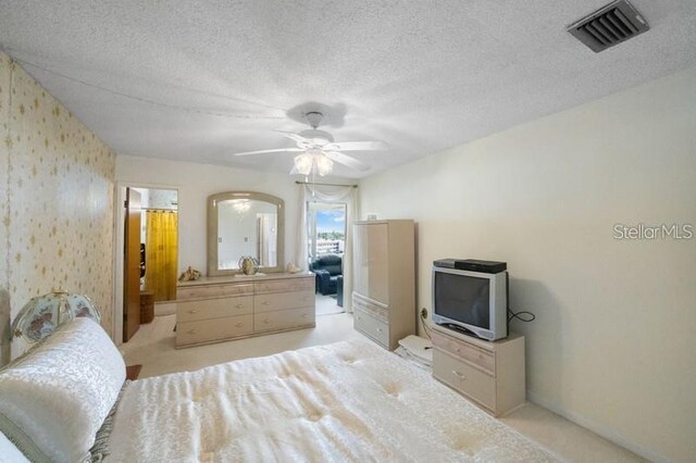 5925 Shore Blvd S Unit 602, Gulfport, FL 33707 - bedroom featuring light colored carpet, a textured ceiling, visible vents, a ceiling fan, and wallpapered walls