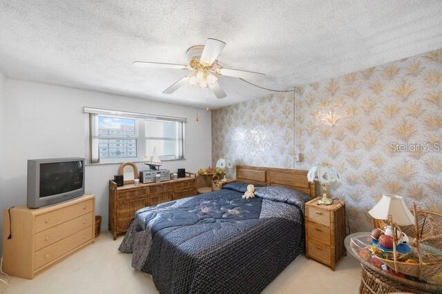 5925 Shore Blvd S Unit 602, Gulfport, FL 33707 - bedroom with wallpapered walls, light carpet, ceiling fan, and a textured ceiling