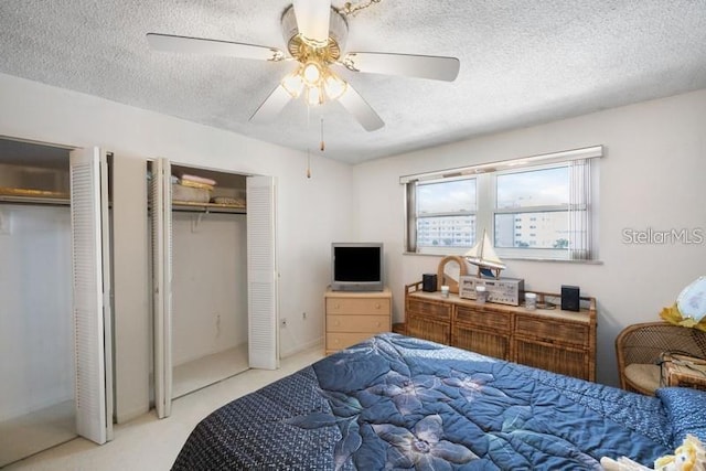 5925 Shore Blvd S Unit 602, Gulfport, FL 33707 - bedroom with a textured ceiling, a ceiling fan, two closets, and light colored carpet