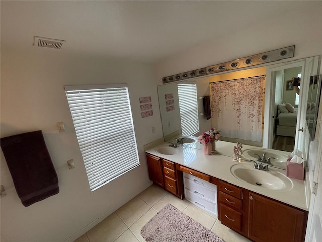 bathroom featuring tile patterned flooring, double vanity, and plenty of natural light