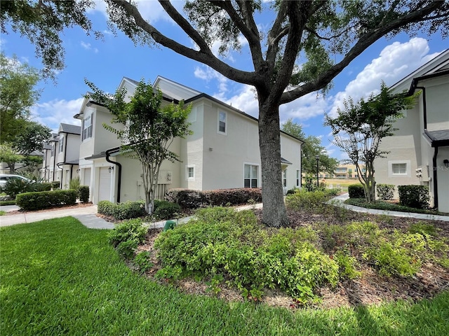 view of side of home featuring stucco siding, a yard, a residential view, and a garage