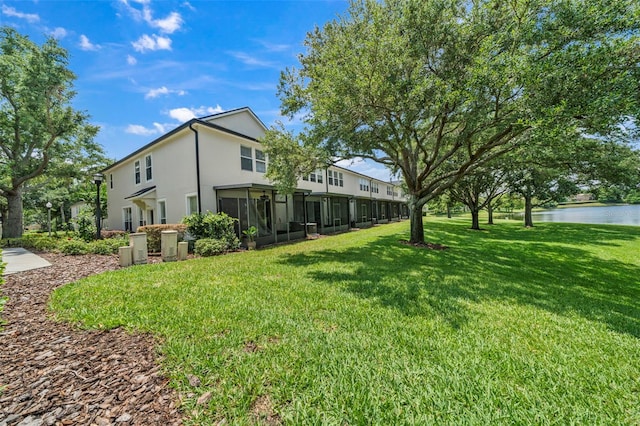 view of green lawn with a sunroom and a water view