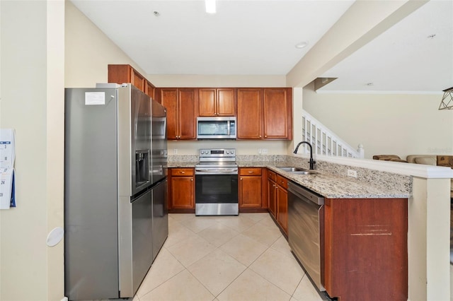 kitchen featuring appliances with stainless steel finishes, a sink, light stone countertops, a peninsula, and light tile patterned floors