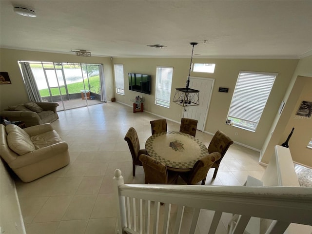 dining space featuring light tile patterned floors, healthy amount of natural light, crown molding, and baseboards