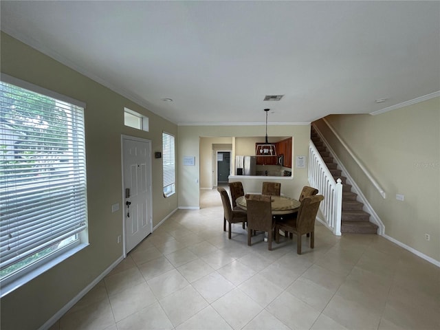dining space featuring plenty of natural light, stairs, baseboards, crown molding, and light tile patterned floors