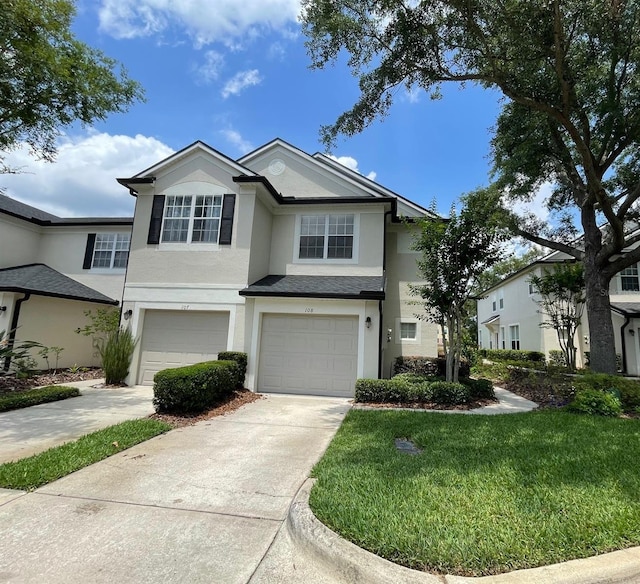 view of front of home with stucco siding, a garage, driveway, and a front yard