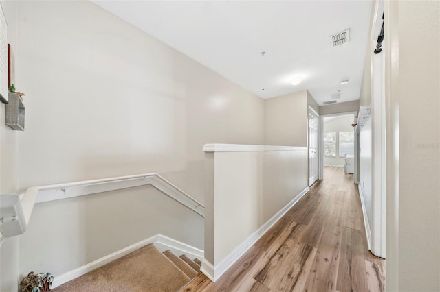 hall with an upstairs landing, wood finished floors, and baseboards