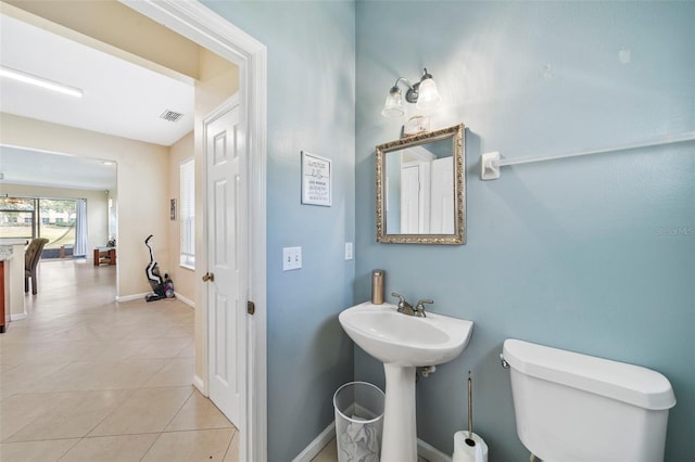 bathroom with tile patterned flooring, toilet, baseboards, and a sink