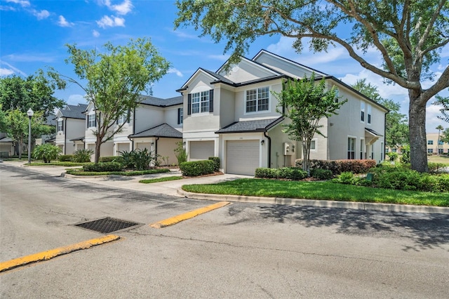 view of front of home with a garage, stucco siding, driveway, and a residential view