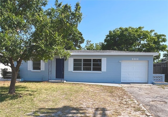 single story home featuring a front lawn, aphalt driveway, and an attached garage