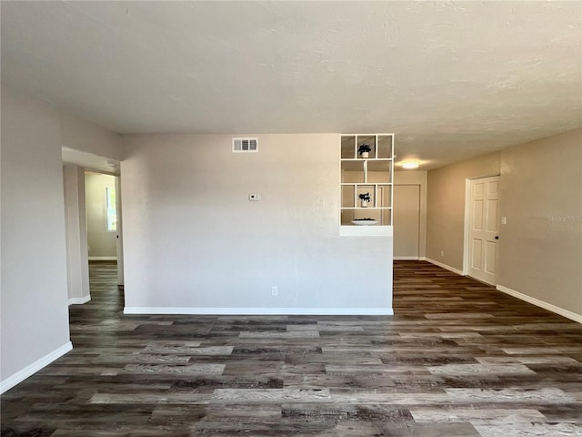 unfurnished living room with dark wood-style flooring, baseboards, and visible vents