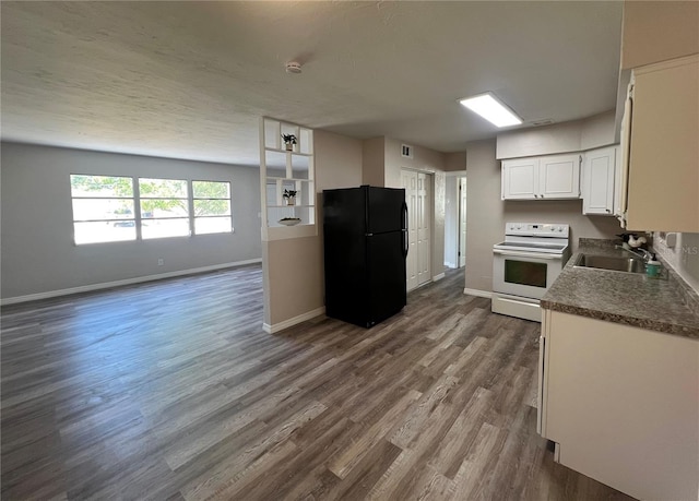 kitchen with a sink, freestanding refrigerator, white cabinetry, baseboards, and electric stove