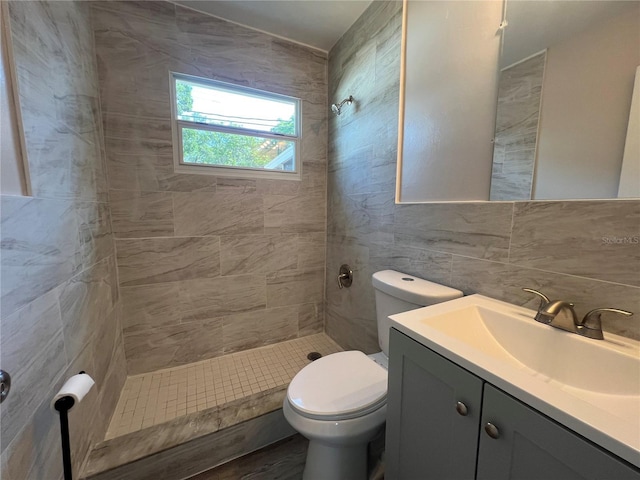 full bathroom featuring tile walls, toilet, tiled shower, vanity, and decorative backsplash
