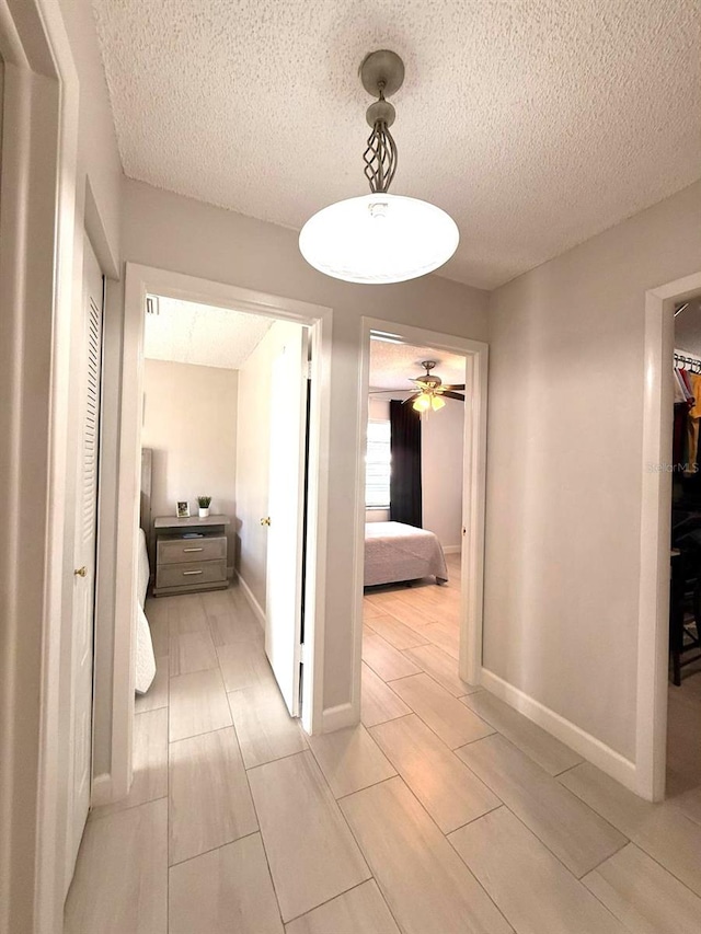 hallway featuring baseboards and a textured ceiling