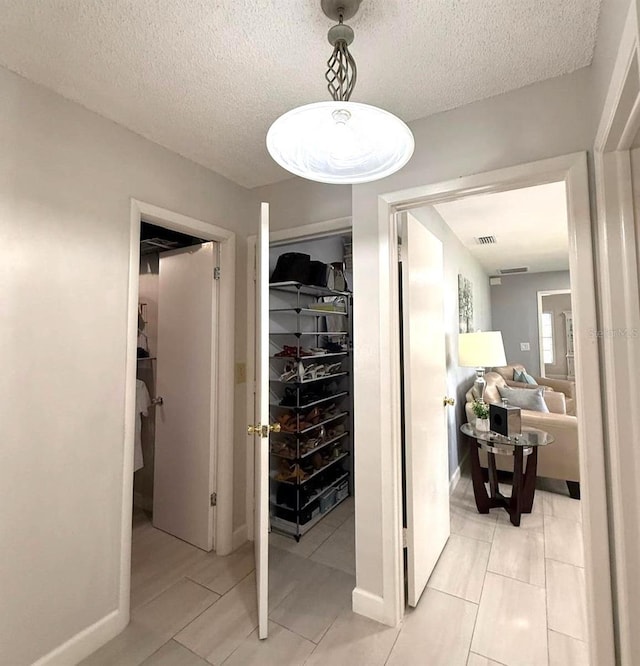 interior space with light tile patterned floors, baseboards, a textured ceiling, and visible vents