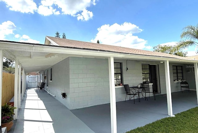 rear view of property featuring a shingled roof and fence