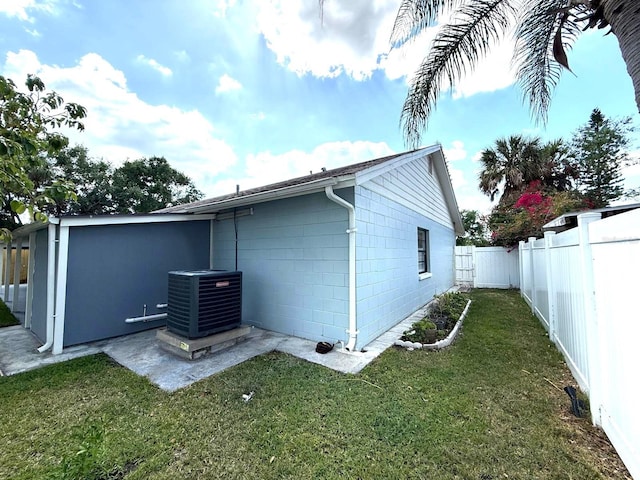 rear view of property with central air condition unit, a lawn, and a fenced backyard